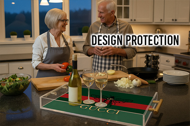Clear acrylic serving tray with gold handles and a custom Gucci-inspired design displayed on a kitchen island with wine glasses, while an older couple wearing aprons chats and prepares food in a modern kitchen, with the text “Design Protection” above.